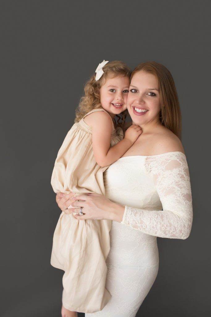 Morgan and daughter Sydney cuddling standing pose dressed in coordinating gowns for maternity photos