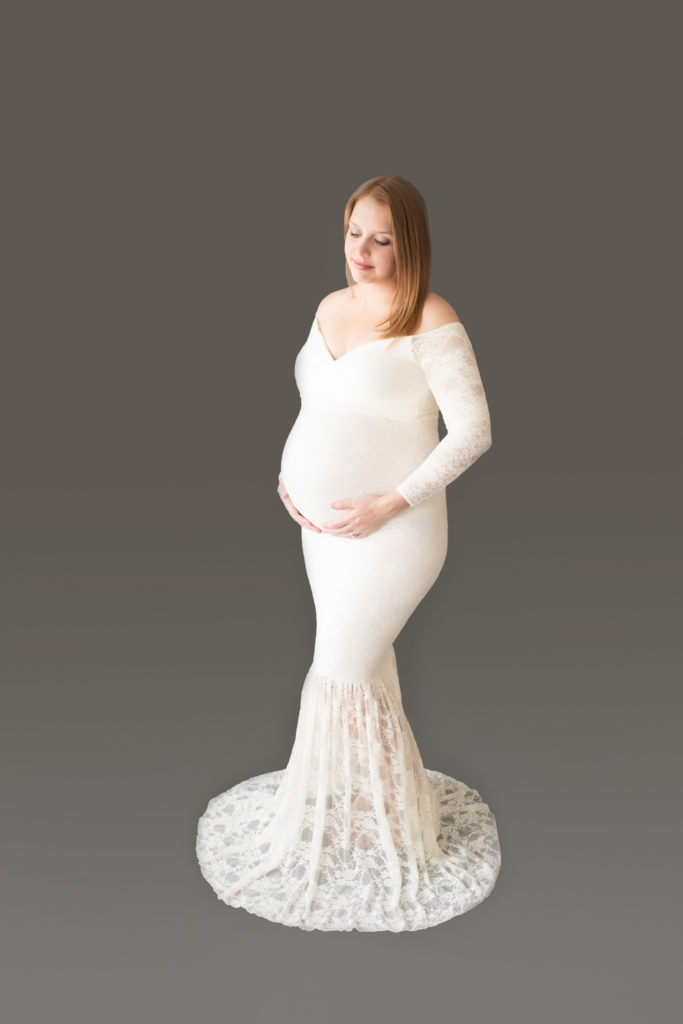 Morgan dressed in lace mermaid maternity gown formal standing pose lgazing at perfect belly bump