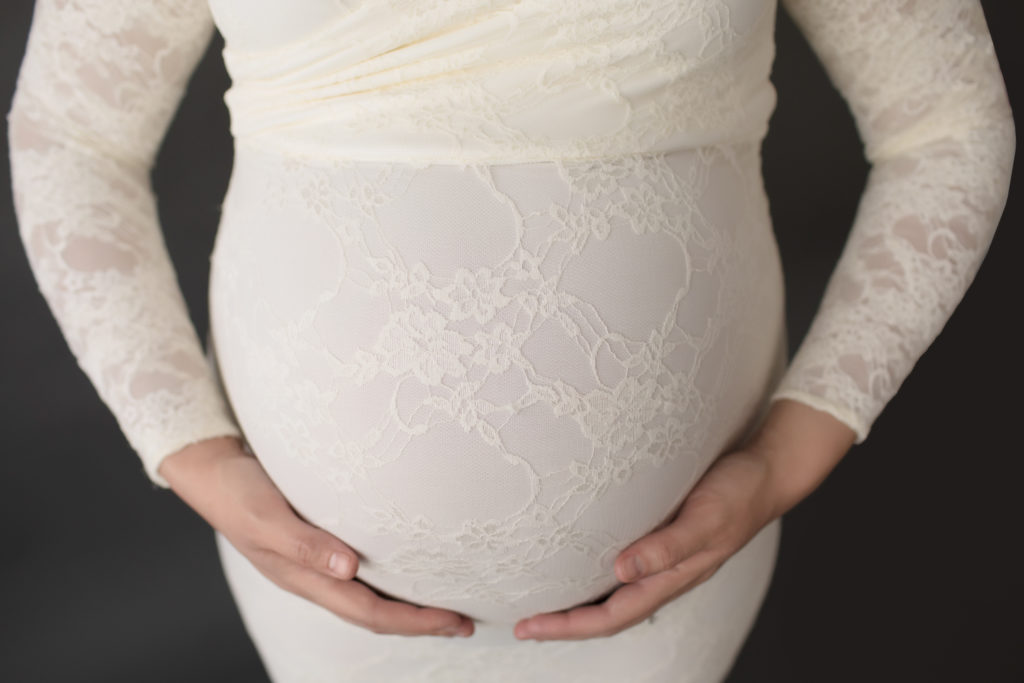 Morgan dressed in lace mermaid maternity gown close up belly with moms hands