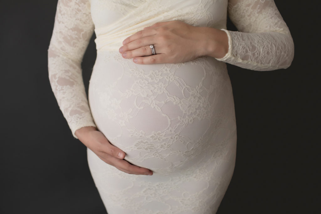 Morgan dressed in lace mermaid maternity gown close up belly with moms hands above and below