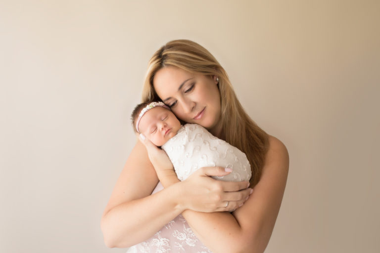 Beautiful Mom in pink lace cuddling newborn girl wrapped in cream photos Gainesville FLorida