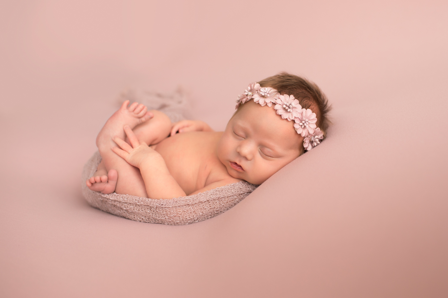 Newborn naked baby girl wrapped in pink on blush blanket with floral crown ...