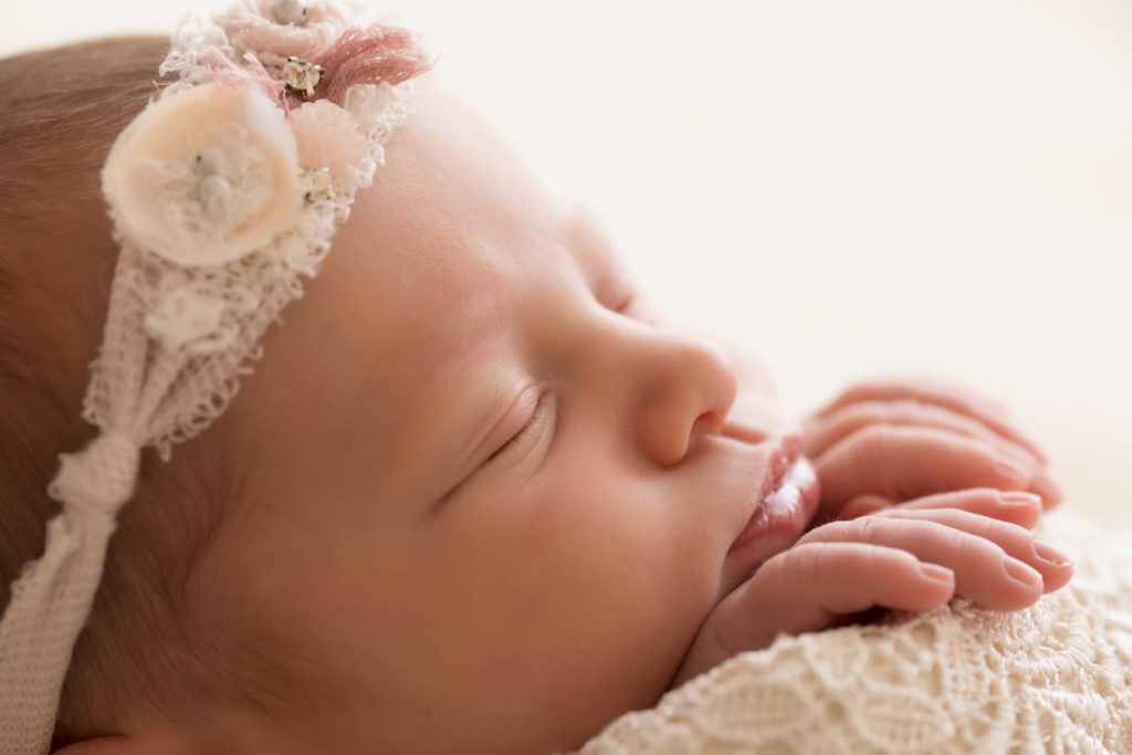 Newborn baby girl Bailey close up profile wrapped in ivory lace with baby fingers wrapped on lace blanket lave headtie Gainesville FL Andrea Sollenberger Photography