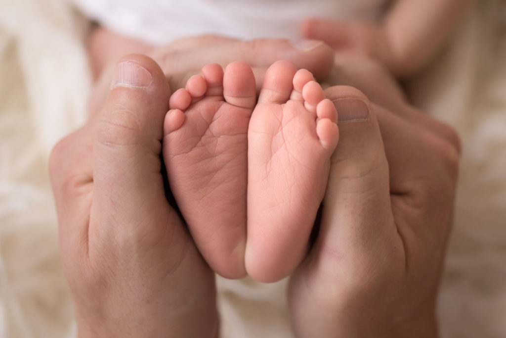 Newborn baby Bailey two tiny baby feet next to dads thumbs Newborn Session Gainesville Florida Andrea Sollenberger Photography