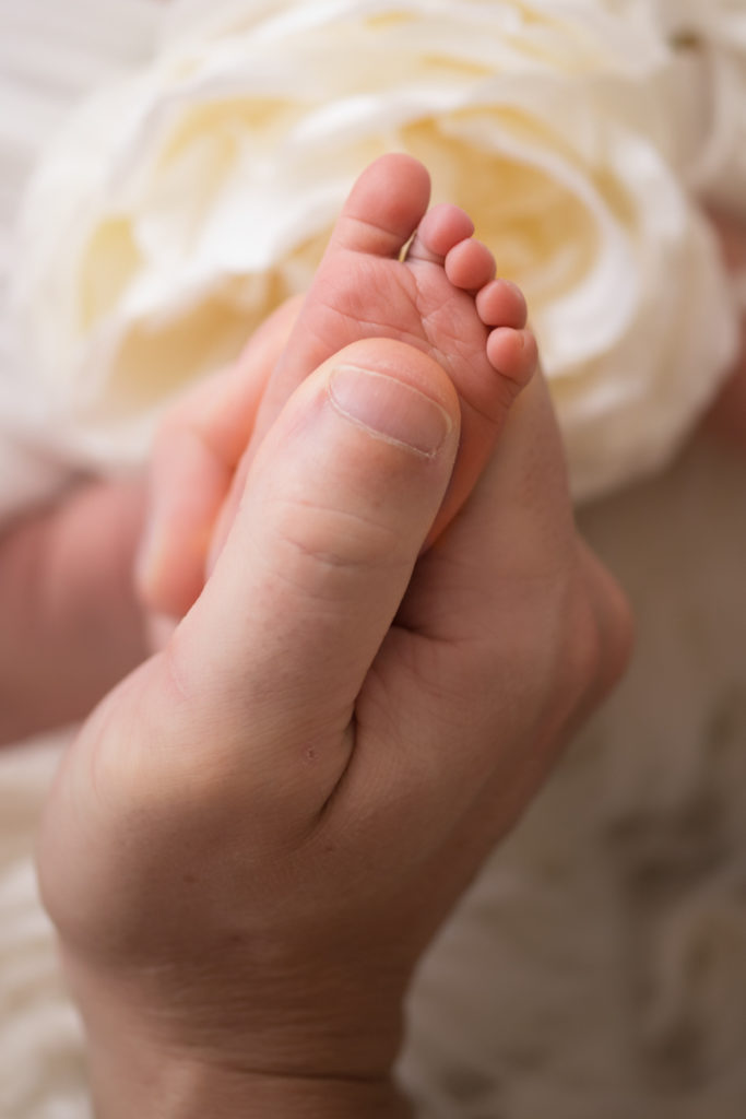 Newborn baby Bailey tiny foot against dad Glenn's big thumb Gainesville FL Andrea Sollenberger Photography