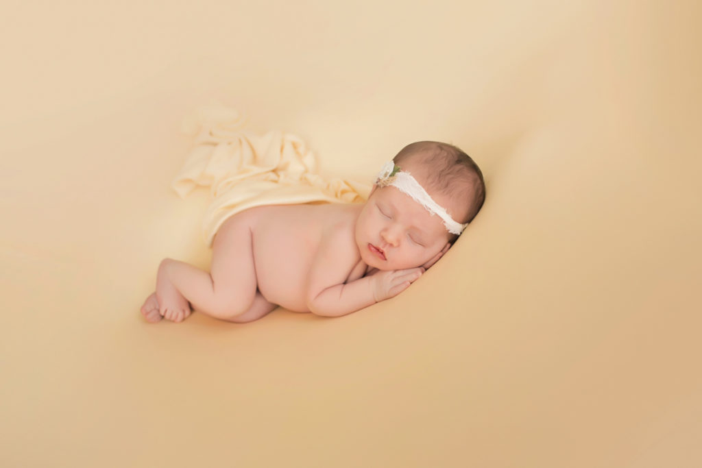 Newborn baby girl Bailey lying on side on buttercream blanket with lace headtie Gainesville FL Andrea Sollenberger Photography