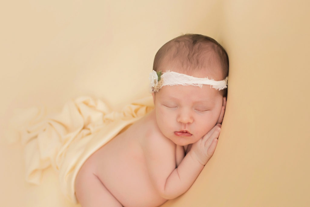Newborn baby girl Bailey lying on side on buttercream blanket head propped up with lace headtie Gainesville FL Andrea Sollenberger Photography