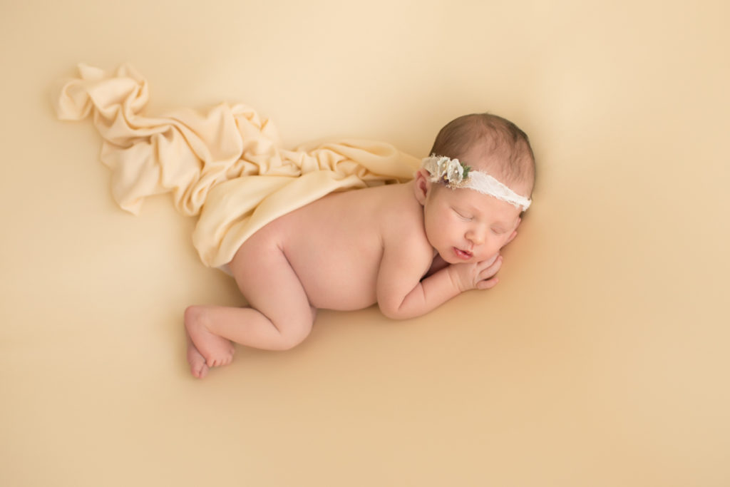 Newborn baby girl Bailey lying on side on buttercream blanket with lace headtie camera from above Gainesville FL Andrea Sollenberger Photography