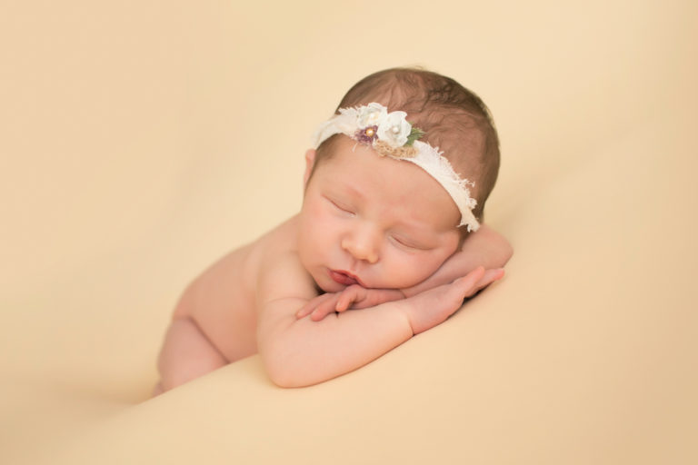 Newborn baby Bailey lying on side on buttercream blanket with lace headtie head propped up on arms at wrists Gainesville FL Andrea Sollenberger Photography
