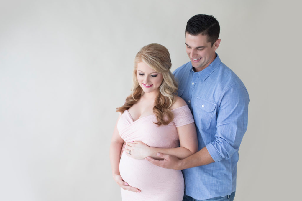 Maternity photos Christina with her man Jamie looking down beautiful belly bump wearing mermaid style full length pale pink lace gown Gainesville Florida