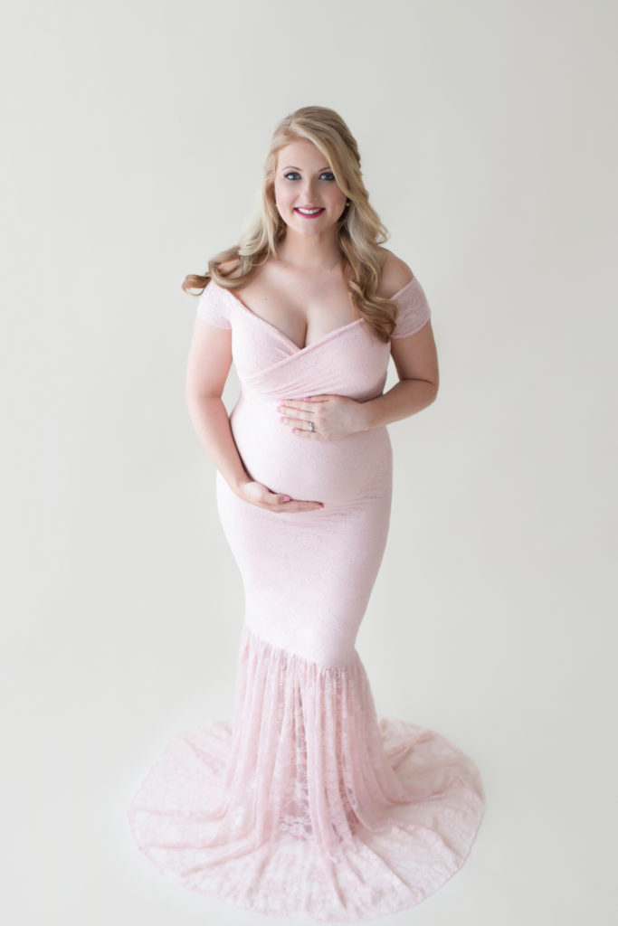 Maternity photos Christina posed fashion cover girl style showing beautiful belly bump wearing mermaid style full length pale pink lace gown Gainesville Florida