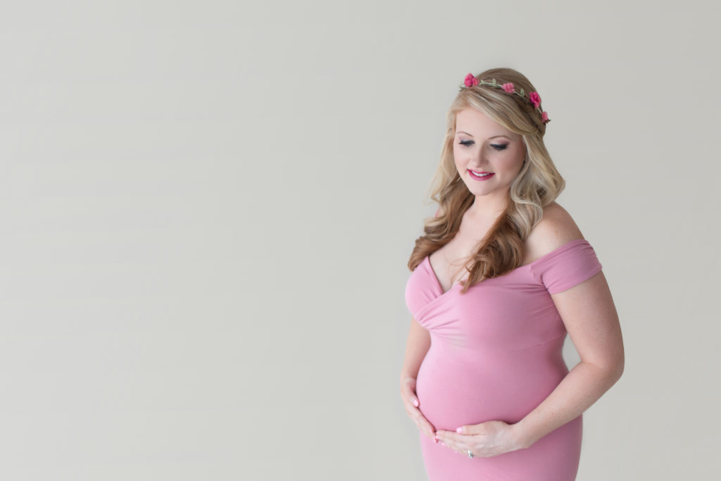 Maternity photos Christina posed standing smiling wearing mermaid style full length rose pink gown with floral crown Gainesville Florida