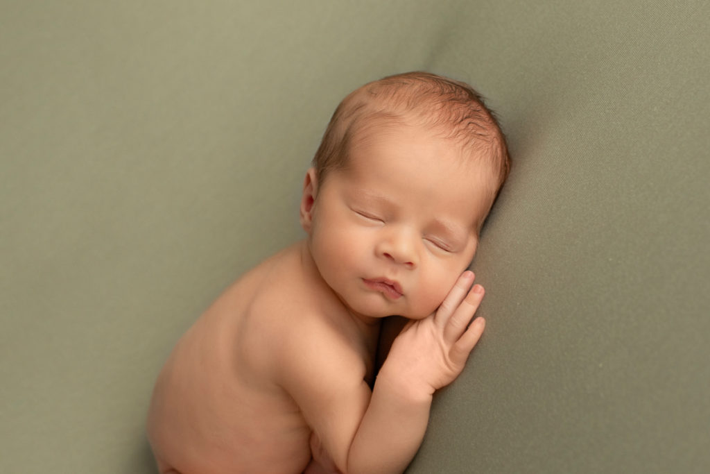 Newborn baby Rowan close up posed on green blanket cheek resting on fingers Gainesvile Florida Photos