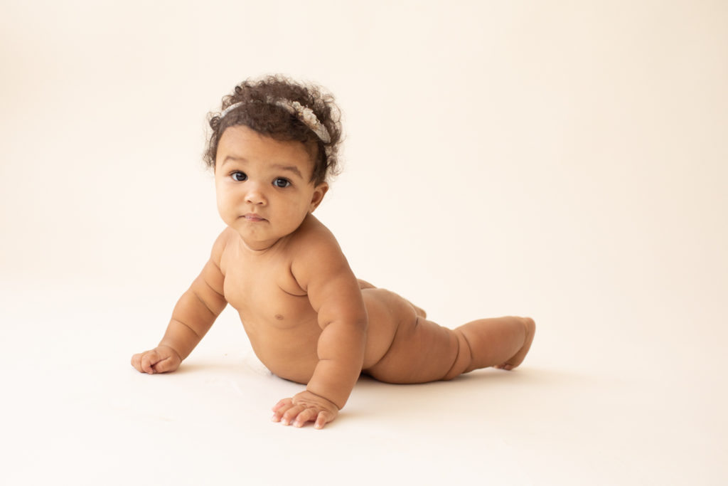 Milestone session 6 months old pushing up naked with soft squishy baby rolls on white floor in Gainesville FL