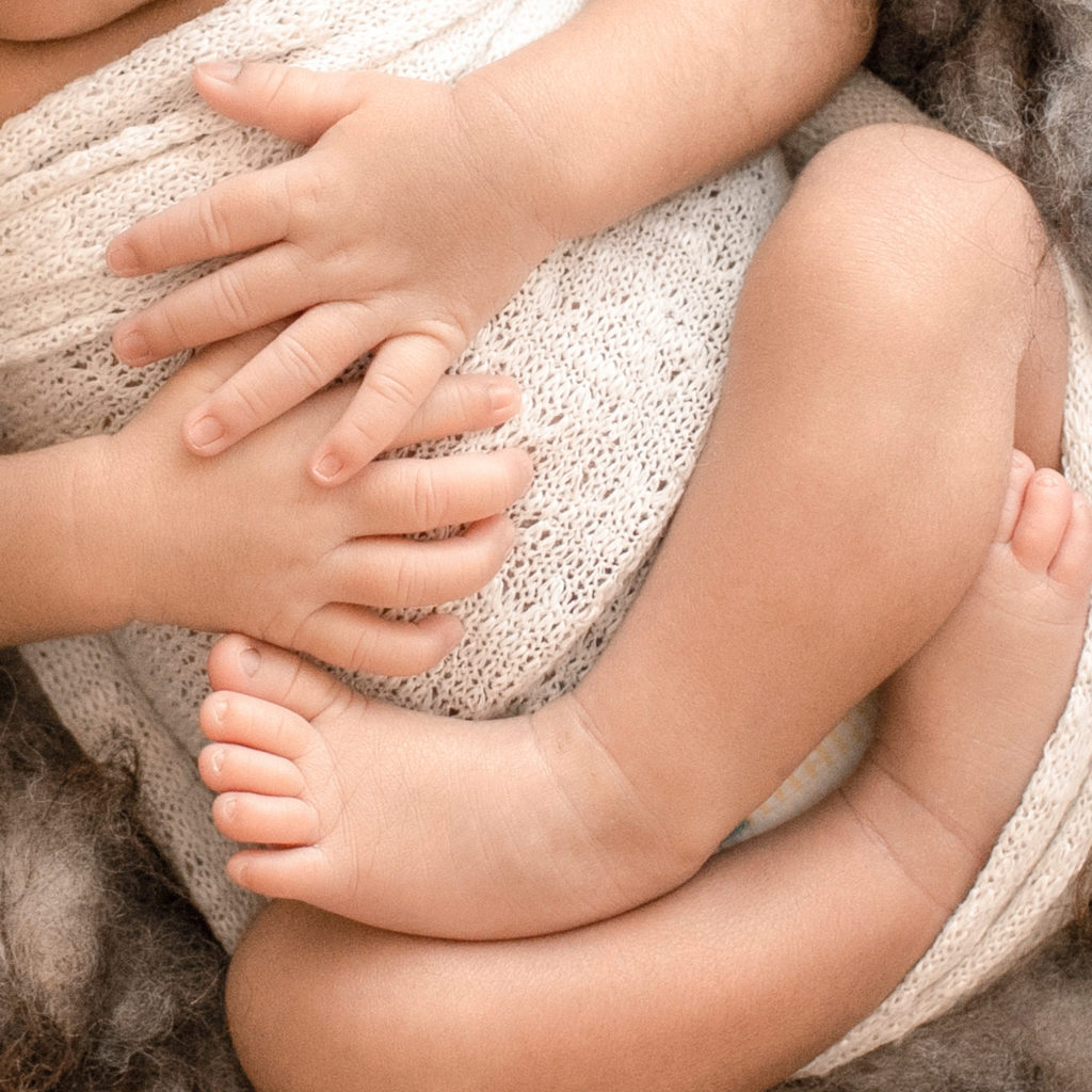 Newborn Jacob photos with full head of hair close up tiny fingers tiny toes wrapped in cream knit wrap on brown fur Gainesville FL