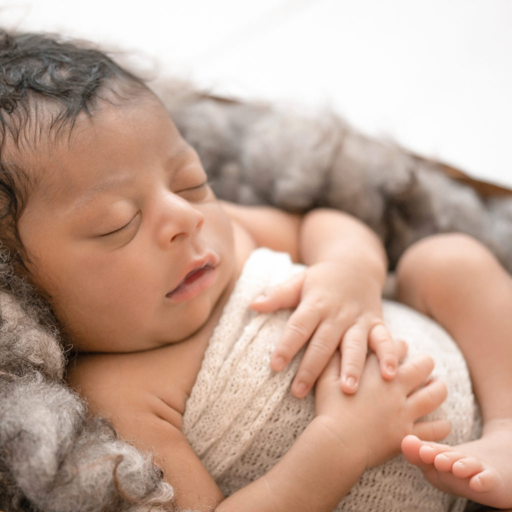 Newborn Jacob photos face close up baby details close up with full head of hair wrapped in knit cream wrap on brown fur Gainesville FL