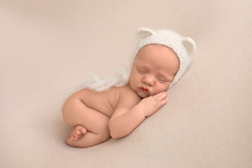 Gainesville Newborn Boy Gavin naked pose on beige blanket with bottom up and white bear hat Andrea Sollenberger Photography