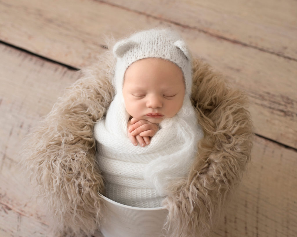 Gainesville Newborn Boy Gavin white knit wrap potato sack and bear hat in white bucket stuffed with beige fur Andrea Sollenberger Photography