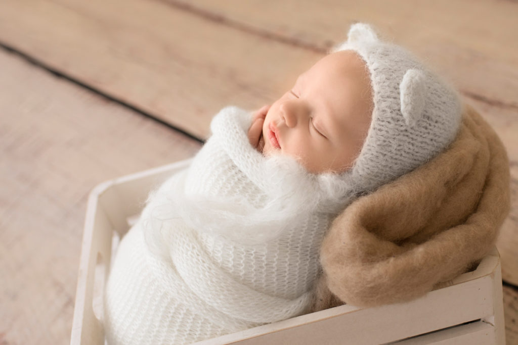 Gainesville Newborn Boy Gavin profile photo potato sack white knit wrap and bear hat on beige blanket in white crate