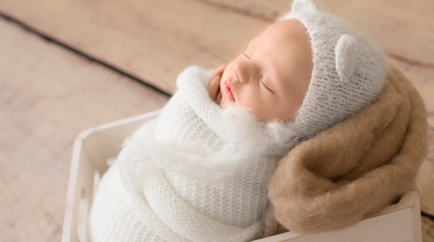 Gainesville Newborn Boy Gavin profile photo potato sack white knit wrap and bear hat on beige blanket in white crate