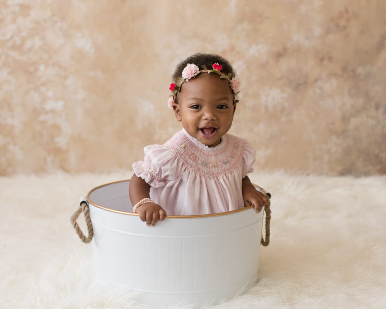 Rose One Year Old Baby Photos sitting in white tub with pink smocked dress and floral crown pearls pink and peach tones Gainesville Florida