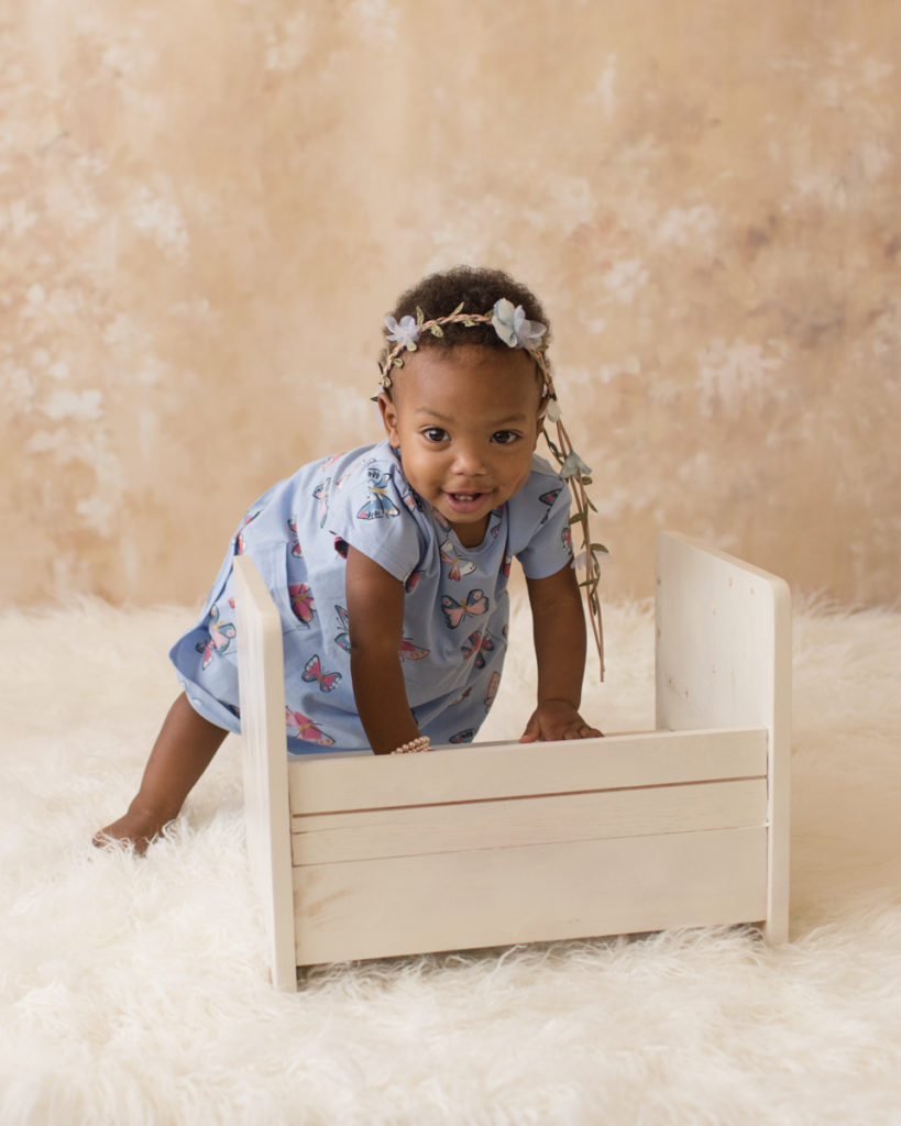 Rose One Year Old Baby Photos pink and peach tones peeking with blue dress and floral crown pearls Gainesville Florida