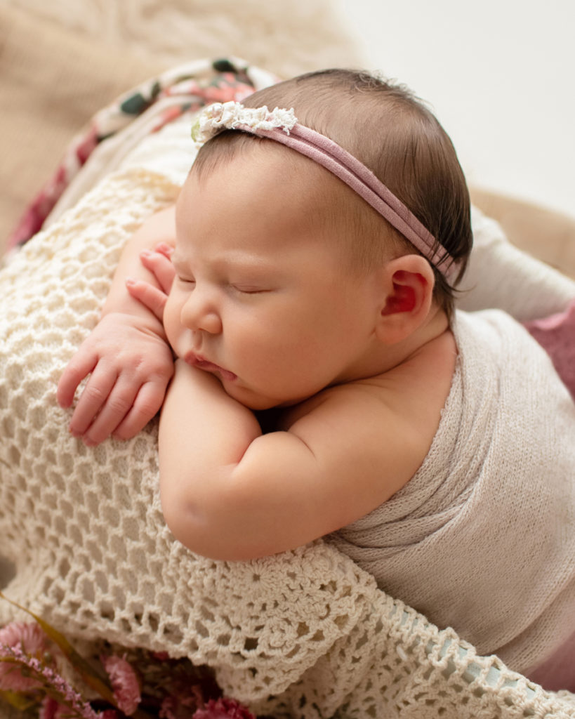 Hensley newborn photos posed sleeping on her arms in drawer draped with ivory lace pink blanket and head tie from above Gainesville Florida Newborn Photography