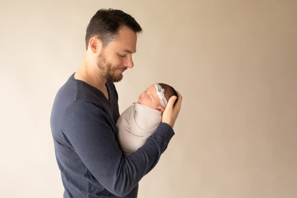 Hensley newborn photos Dad holding tiny swaddled baby in beige wrap profile Gainesville Florida Newborn Photography