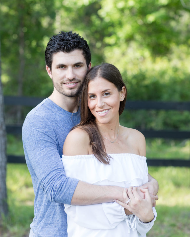 Gorgeous married couple dark hair dressed in blue and white posed at fence light filled outside photo Williston Florida