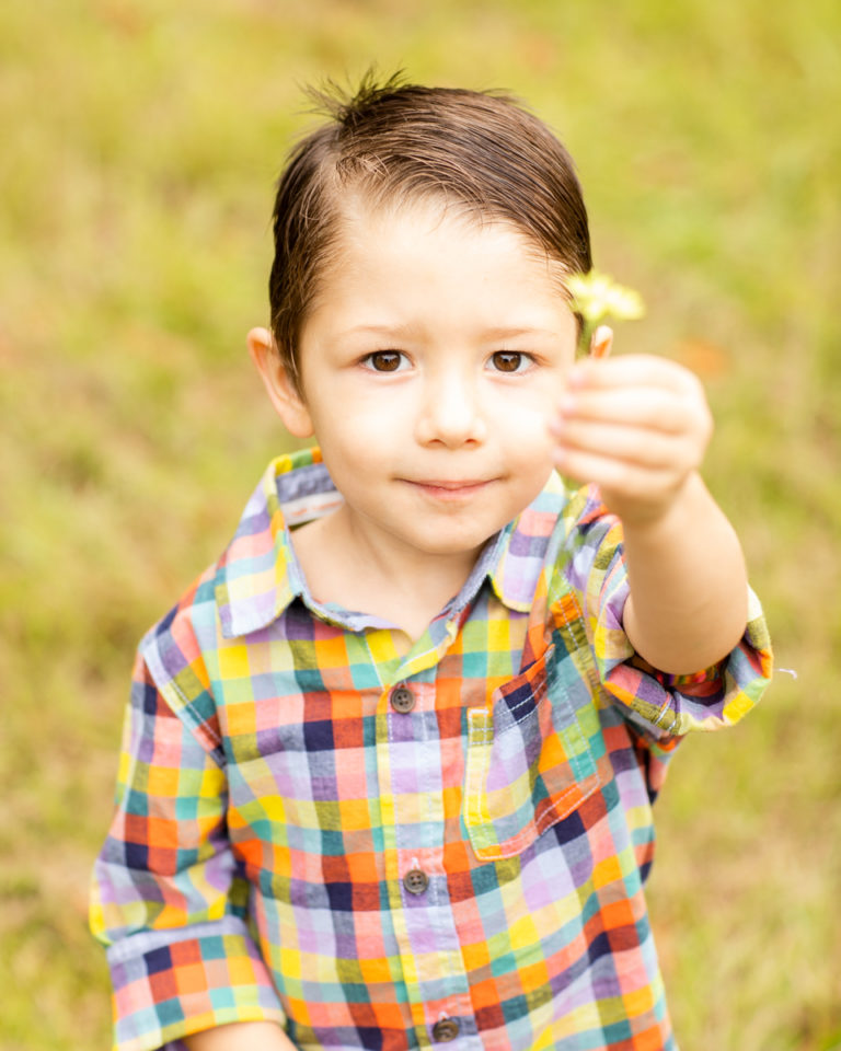 Three Year Old Boy with big brown eyes has flower for mom at Horseshoe Farm Alachua Florida