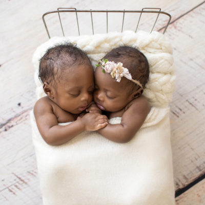 Twin Newborns Samuel and Sophia posed cuddling holding hands in metal newborn bed covered with cream blanket textured pillow distressed white floor in Gainesville Florida newborn photos taken from above