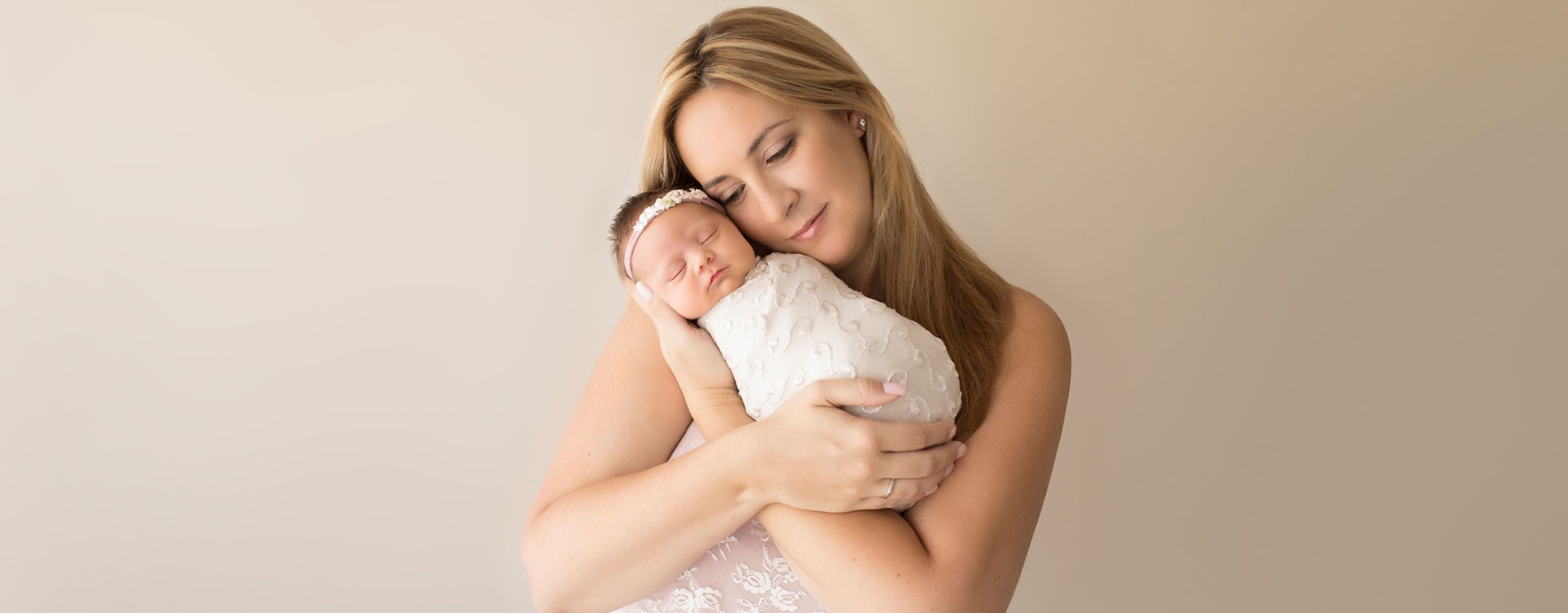 Gorgeous Mom in pink lace cuddling newborn girl wrapped in lace cream photos Gainesville FLorida