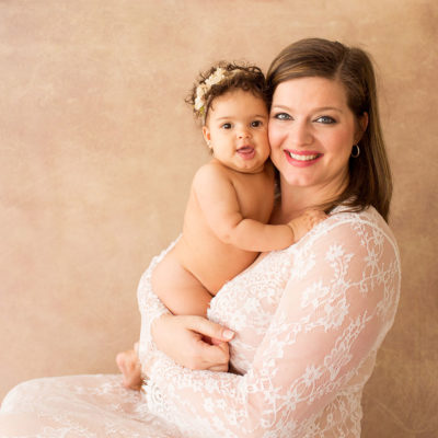 Gorgeous mom in white lace cuddling beautiful naked 9 minth girl with curly hair and ivory crown