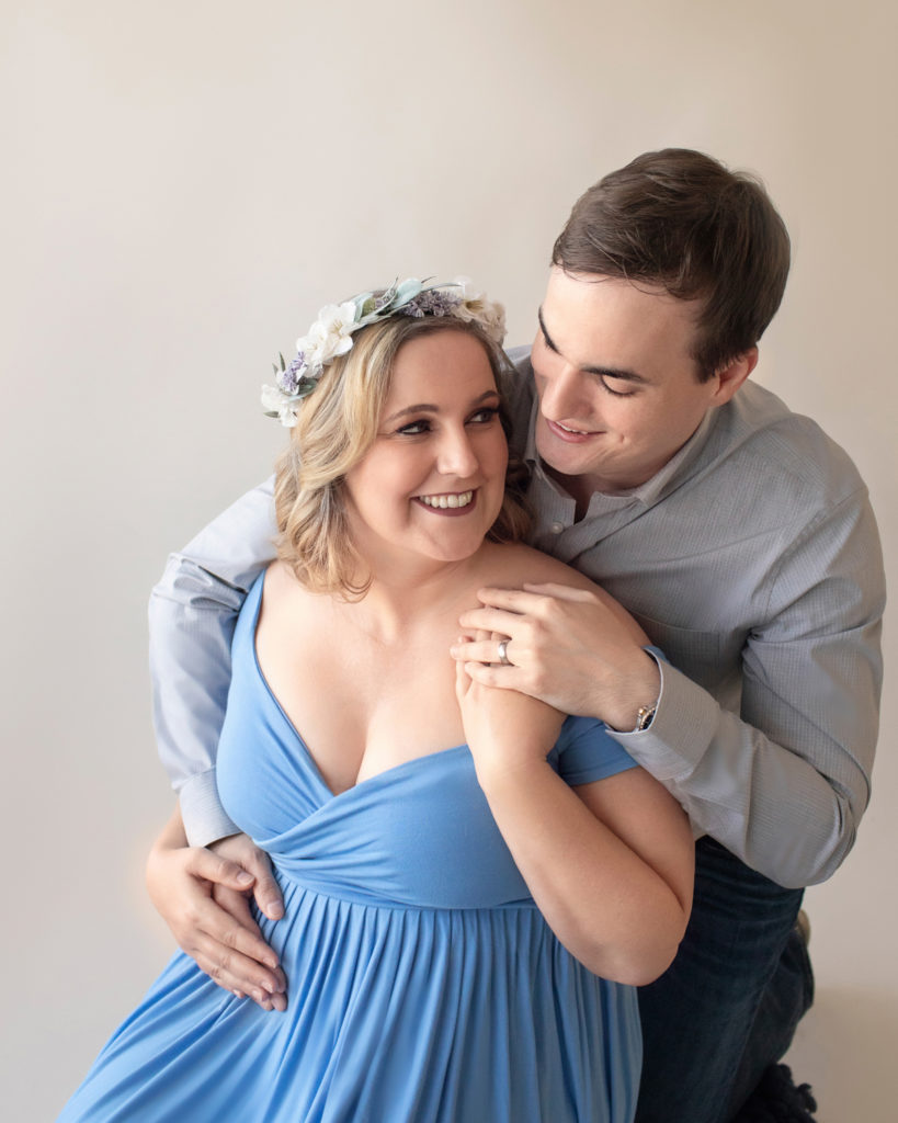 Maternity couple looking at each other Katie in light blue draped maternity gown with floral crown and husband Ben in denim and grey Gainesville Florida Maternity portraits