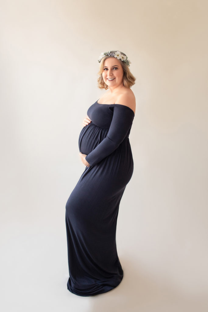 Maternity Katie in navy blue draped maternity gown with floral crown full length profile of perfect baby bump smiling at camera Gainesville Florida Maternity portraits