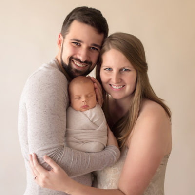 Newborn wrapped baby with tender mom and dad cuddle first family portrait soft neutral colors smiling at camera Gainesville FL newborn photography