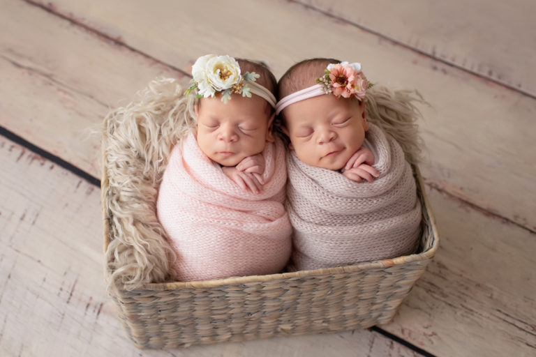 Newborn Twin girl photos baby smile Janae and Renae in pink handmade knit wraps and floral crown head ties in a fur stuffed basket