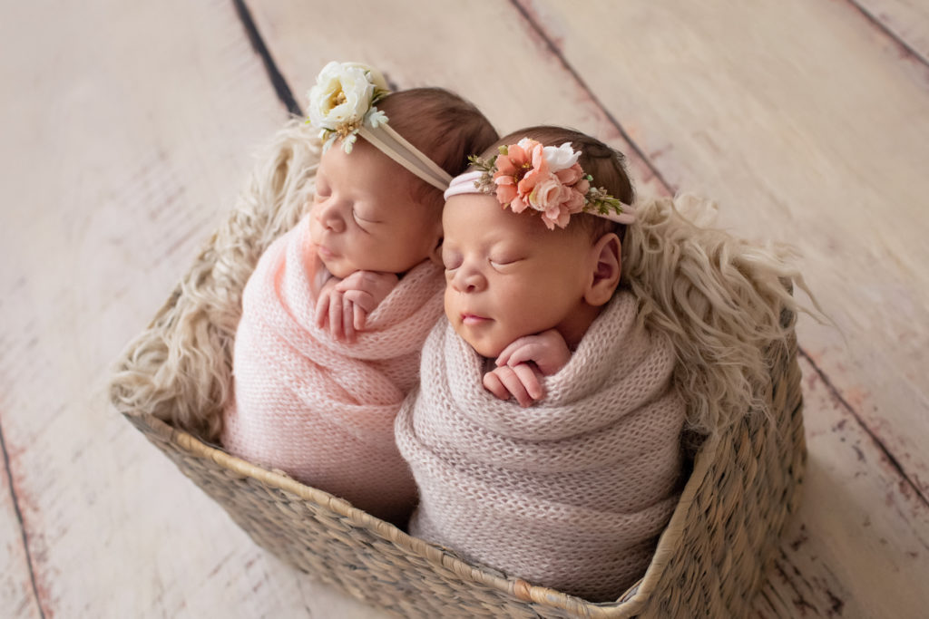 Newborn Twin girl photos Janae and Renae in pink handmade knit wraps and floral crown head ties in a fur stuffed basket