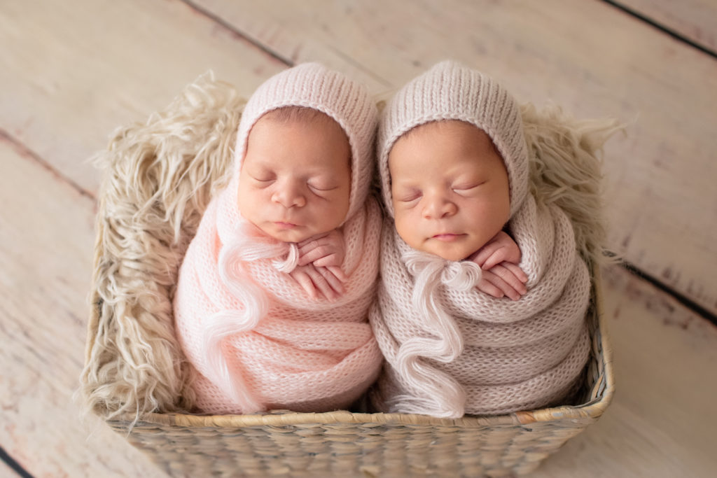 Newborn Twin girl photos Janae and Renae in pink handmade knit potato sack wraps and bonnets in a fur stuffed basket