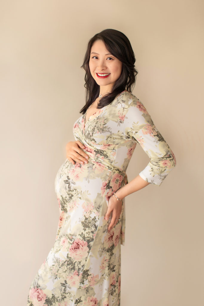 Maternity photos mom wearing floral pink and sage maternity gown in an ivory jersey fabric profile shot smiling at camera Gainesville Florida Maternity Photographer