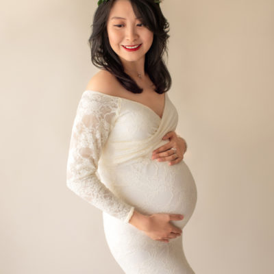 Maternity photo pregnant mom in elegant ivory lace long sleeve fitted gown with circular train wearing ivory floral crown looking toward her shoulder close up Gainesville Florida Maternity Photographer