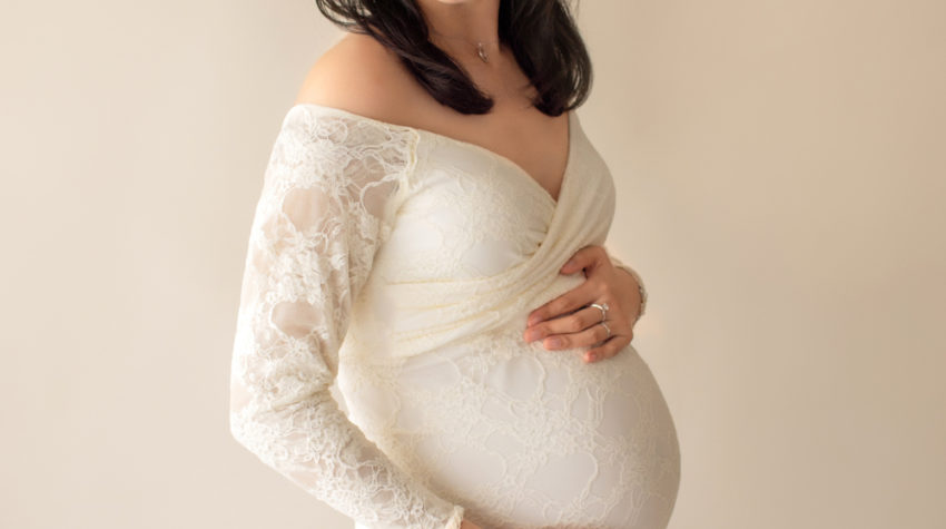 Maternity photo pregnant mom in elegant ivory lace long sleeve fitted gown with circular train wearing ivory floral crown looking toward her shoulder close up Gainesville Florida Maternity Photographer