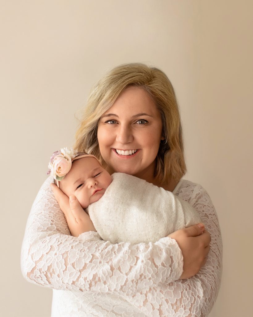 Gainesville Newborn moments Mom dressed in lace smiling hugging and cherishing cuddle time with her tiny newborn baby girl Chloe in cream wrap and floral headband Gainesville Florida newborn photography