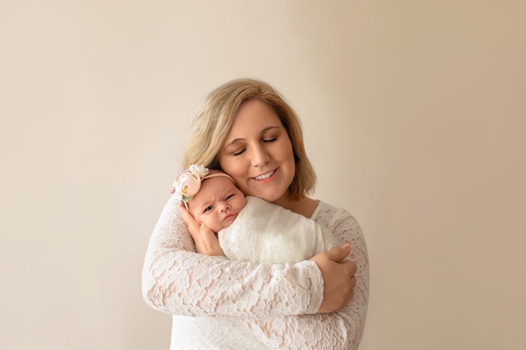 Gainesville Newborn moments Mom dressed in lace hugging and cherishing cuddle time with her tiny newborn baby girl Chloe in cream wrap and floral headband Gainesville Florida newborn photography