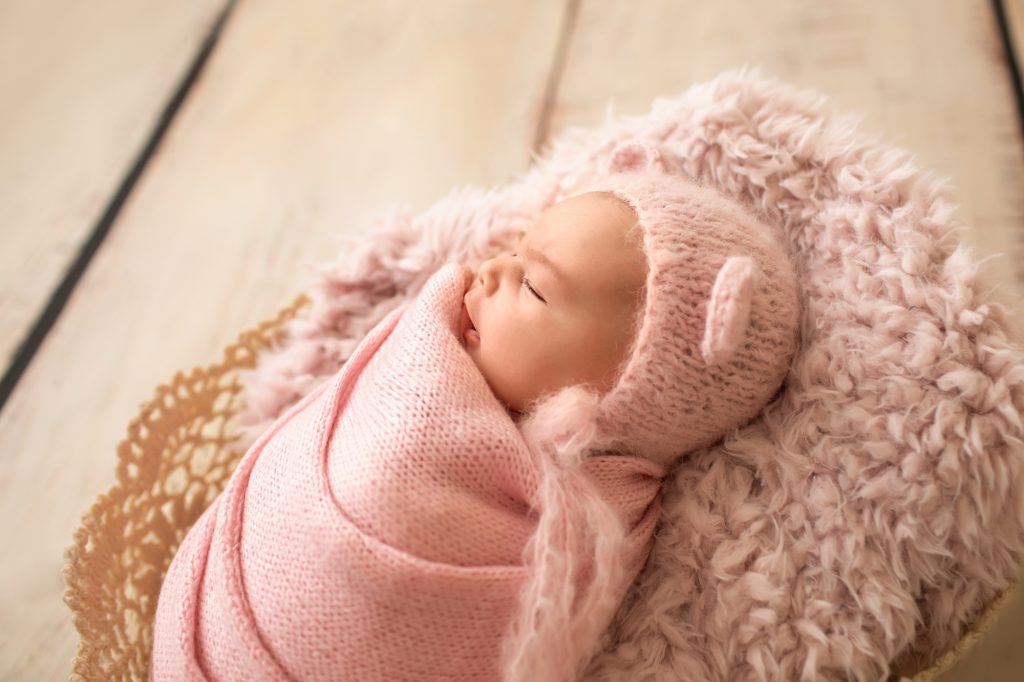 Gainesville Newborn moments newborn baby girl swaddled in pink knit wrap and bear bonnet photo with backlight Gainesville Florida newborn photography