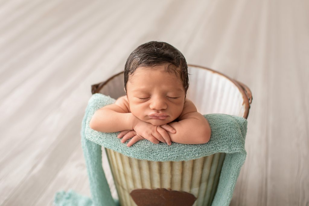 newborn boy Christian posed naked baby in a metal bucket with aqua on grey floor Gainesville Fl newborn picture