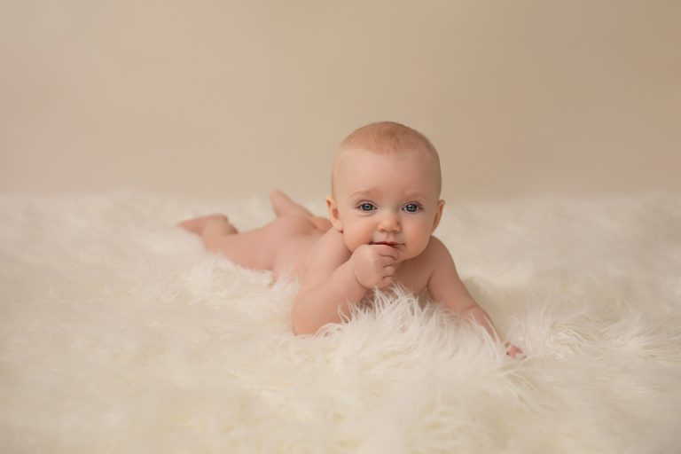 six month naked baby Rachel with soft baby skin posed beautifully on white fur lying on her tummy family heirloom photos