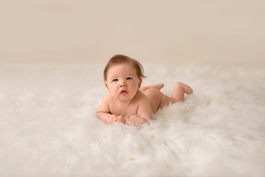 Garrett posed naked soft baby skin propped on elbows on soft white fur looking at camera