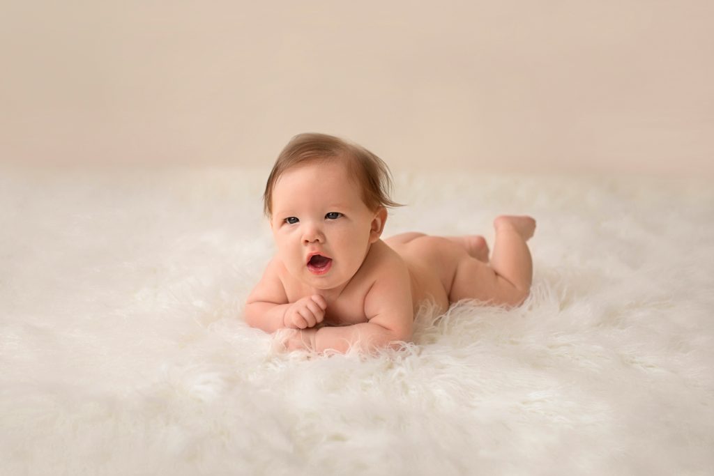 Garrett posed naked soft baby skin playfully propped on elbows on soft white fur