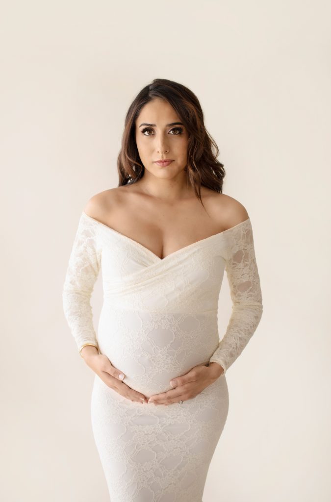 Gorgeous pregnant mom dressed in long sleeved ivory lace mermaid maternity gown with sultry sexy eyes maternity pictures